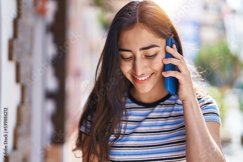 Young hispanic girl smiling confident talking on the smartphone at street