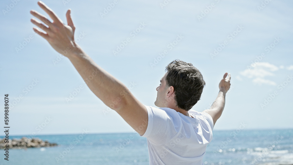 Young hispanic man breathing with arms open at beach Young hispanic man breathing with arms open at beach