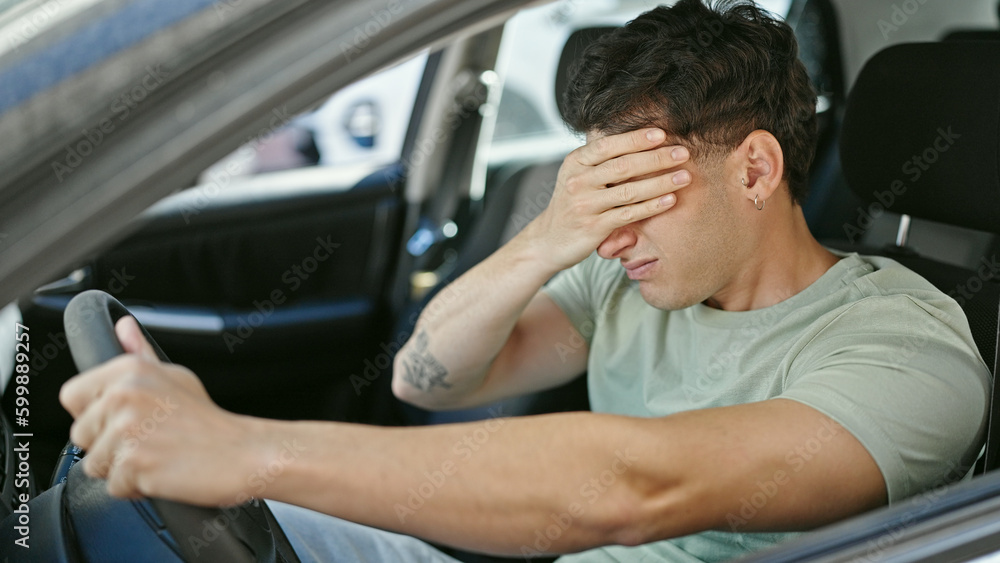 Young hispanic man driving car stressed at street