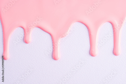 Fototapeta Naklejka Na Ścianę i Meble -  Pink liquid drops of paint color flow down on white canvas. Abstract art. Light pink paint dripping on the white wall with copy space..
