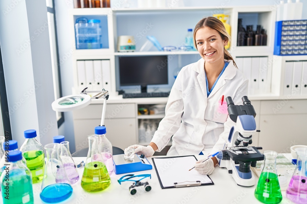 Young hispanic woman scientist weighing diamond writing report at laboratory Young hispanic woman scientist weighing diamond writing report at laboratory
