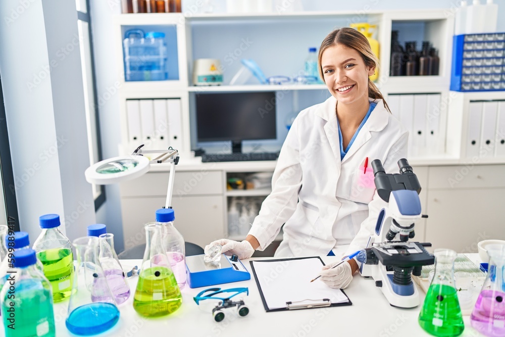 Young hispanic woman scientist weighing diamond writing report at laboratory