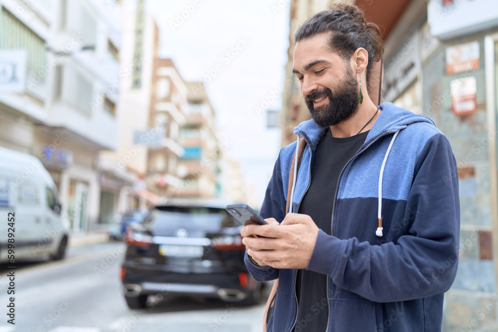 Young hispanic man musician using smartphone holding guitar case at street Young hispanic man musician using smartphone holding guitar case at street