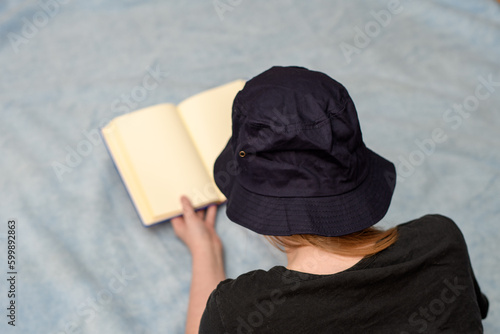 Kobieta czytająca książkę na kocu w kapeluszu przeciwsłonecznym