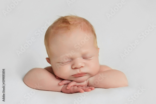 Newborn baby lies on the handles.Newborn baby is sleeping on white blanket.