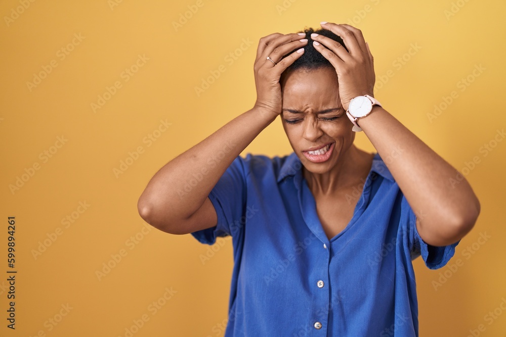 African american woman standing over yellow background suffering from headache desperate and stressed because pain and migraine. hands on head. African american woman standing over yellow background suffering from headache desperate and stressed because pain and migraine. hands on head.