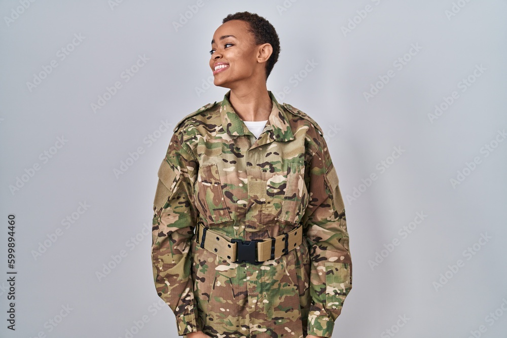 Beautiful african american woman wearing camouflage army uniform looking away to side with smile on face, natural expression. laughing confident. Beautiful african american woman wearing camouflage army uniform looking away to side with smile on face, natural expression. laughing confident.