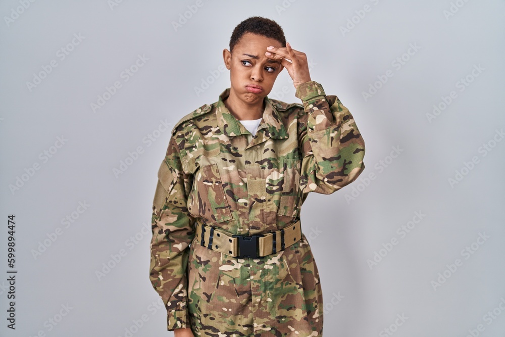 Beautiful african american woman wearing camouflage army uniform worried and stressed about a problem with hand on forehead, nervous and anxious for crisis
