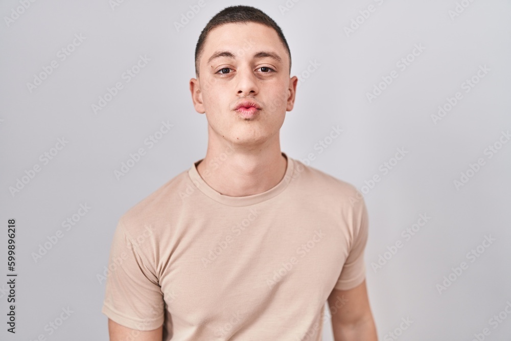 Young man standing over isolated background looking at the camera blowing a kiss on air being lovely and sexy. love expression. Young man standing over isolated background looking at the camera blowing a kiss on air being lovely and sexy. love expression.
