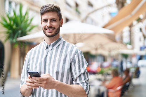 Young caucasian man smiling confident using smartphone at coffee shop terrace