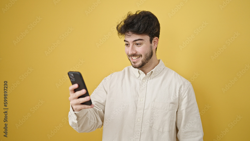 Young hispanic man using smartphone smiling over isolated yellow background Young hispanic man using smartphone smiling over isolated yellow background