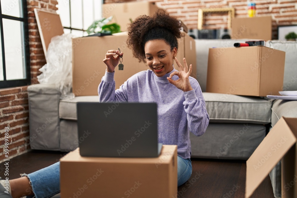 Young african american woman showing keys of new home on video call doing ok sign with fingers, smiling friendly gesturing excellent symbol Young african american woman showing keys of new home on video call doing ok sign with fingers, smiling friendly gesturing excellent symbol