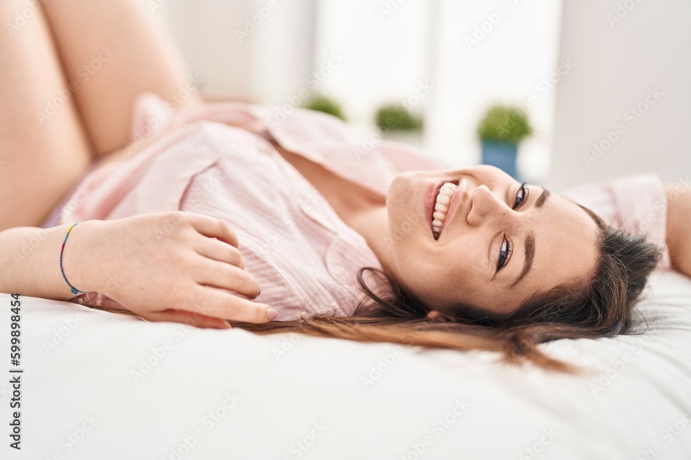 Obraz premium Young woman smiling confident lying on bed at bedroom