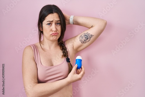 Young brunette woman using roll on deodorant depressed and worry for distress  crying angry and afraid. sad expression.
