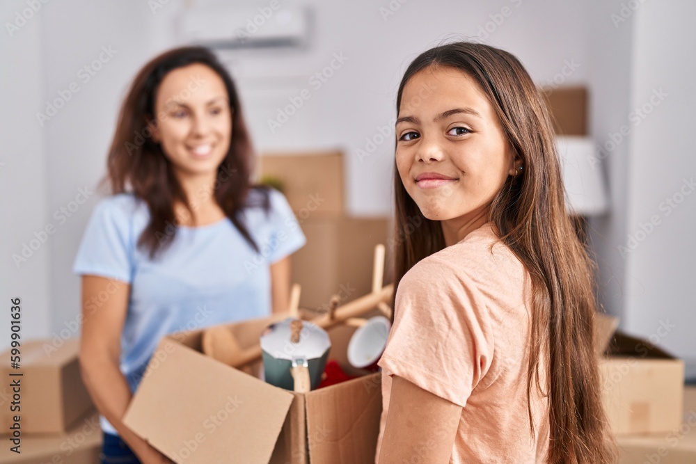 Woman and girl mother and daughter holding package at new home Woman and girl mother and daughter holding package at new home