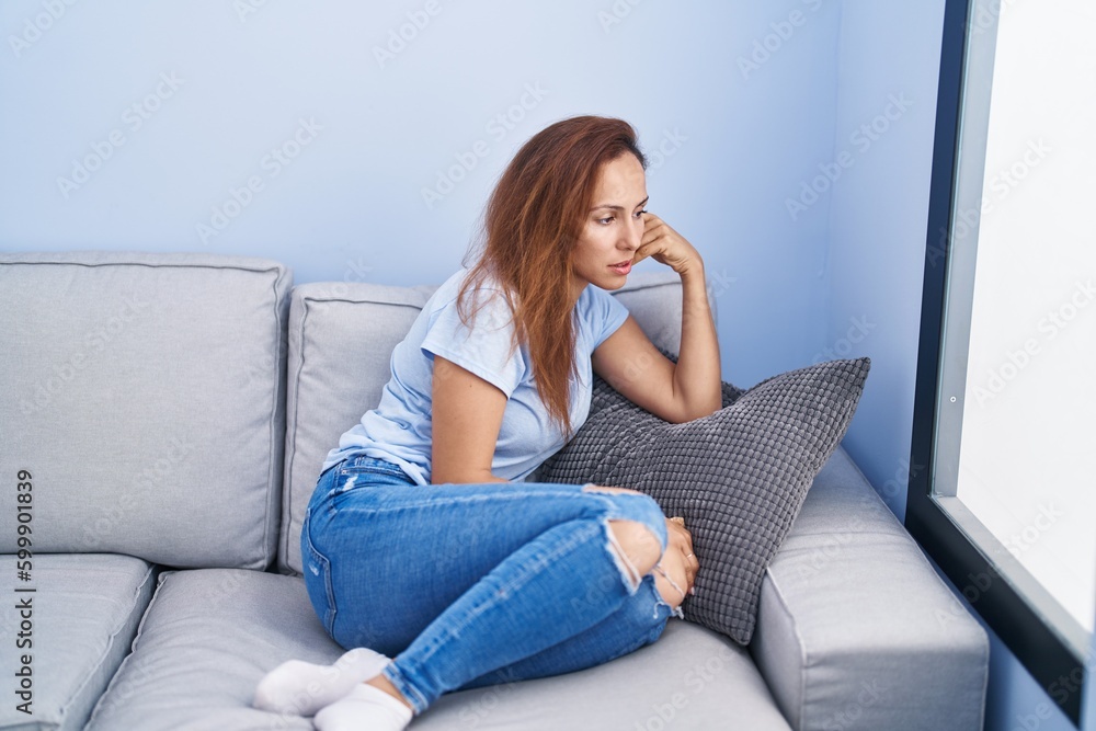 Young woman stressed sitting on sofa at home Young woman stressed sitting on sofa at home
