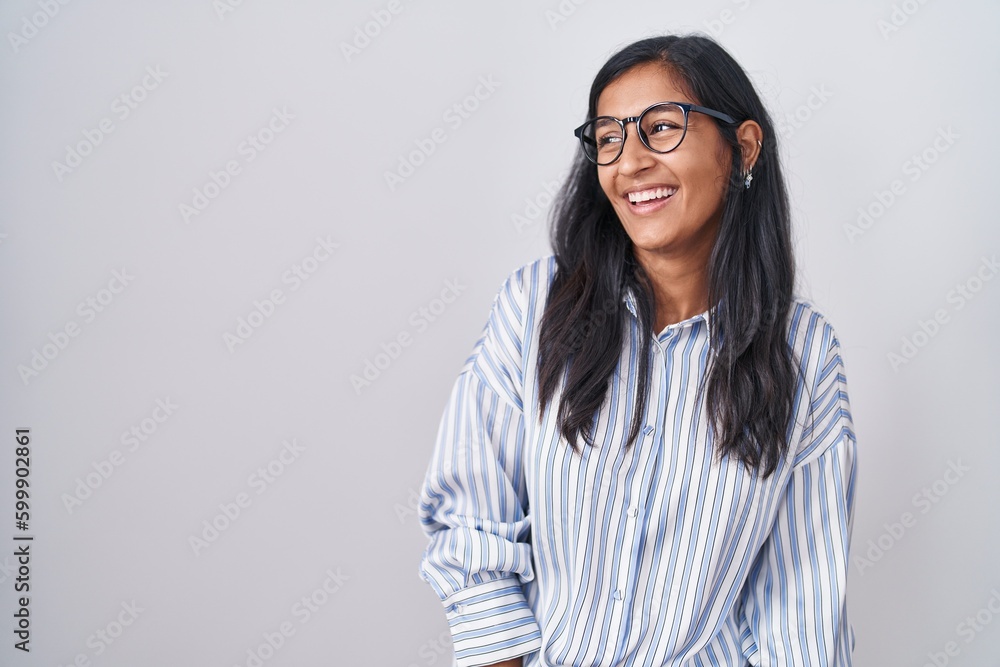 Young hispanic woman wearing glasses looking away to side with smile on face, natural expression. laughing confident.