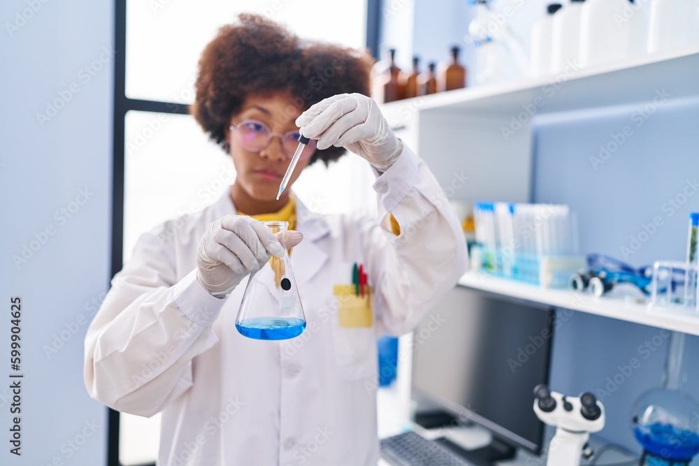 African american woman scientist pouring liquid on test tube at laboratory African american woman scientist pouring liquid on test tube at laboratory