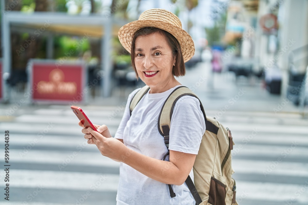 Middle age woman tourist smiling confident using smartphone at street