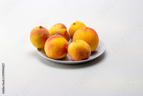 ripe peaches in a shallow dish, on a white milky background.