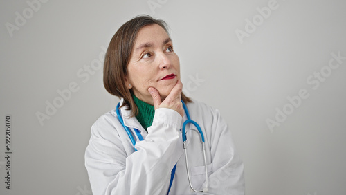 Mature hispanic woman with grey hair doctor standing with doubt expression thinking over isolated white background