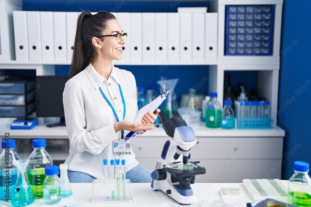 Young brunette woman working at scientist laboratory looking to side, relax profile pose with natural face and confident smile. Young brunette woman working at scientist laboratory looking to side, relax profile pose with natural face and confident smile.
