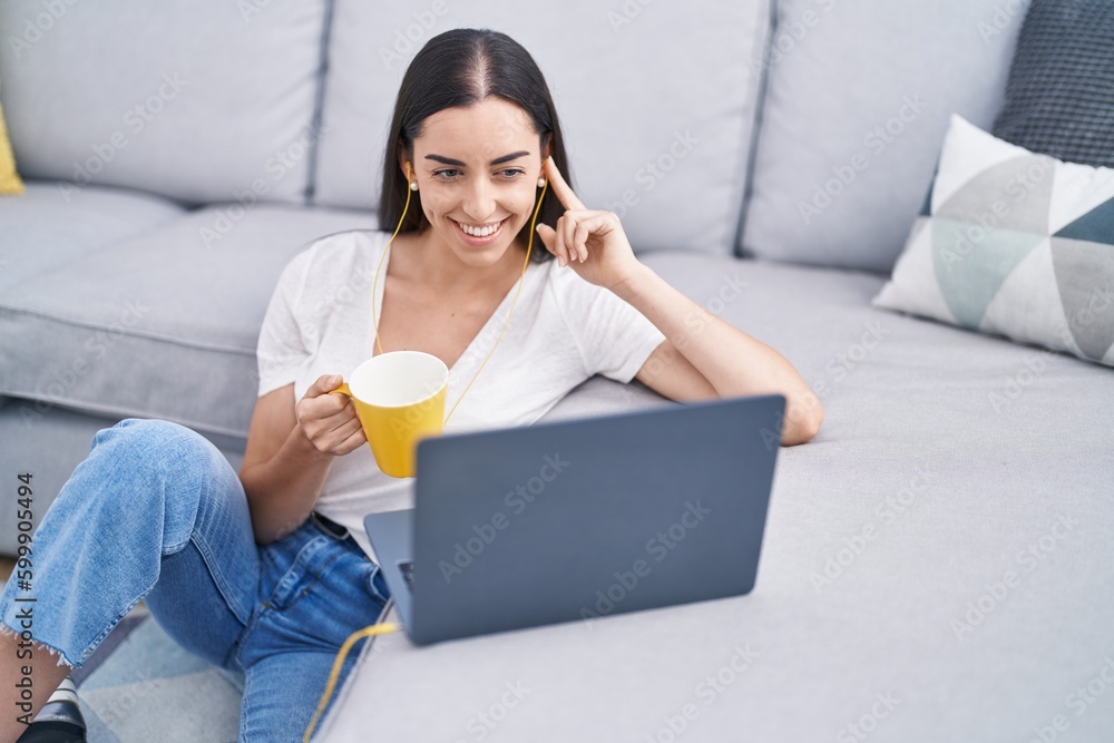 Young hispanic woman using laptop drinking coffee at home Young hispanic woman using laptop drinking coffee at home