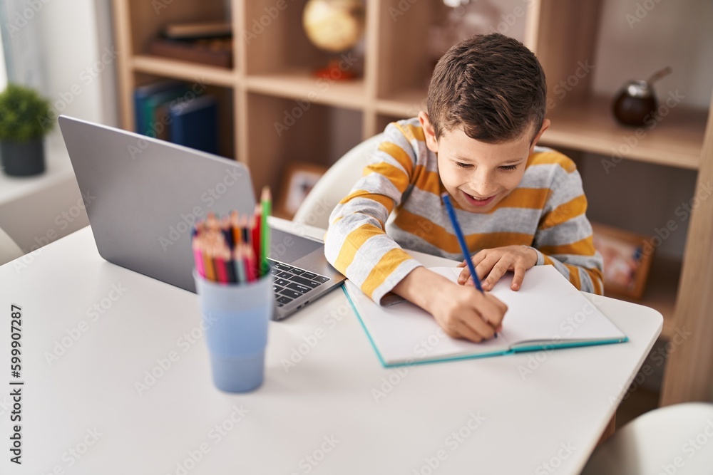 Blond child studying sitting on table at home Blond child studying sitting on table at home