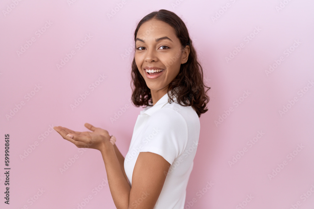 Young hispanic woman wearing casual white t shirt pointing aside with hands open palms showing copy space, presenting advertisement smiling excited happy Young hispanic woman wearing casual white t shirt pointing aside with hands open palms showing copy space, presenting advertisement smiling excited happy
