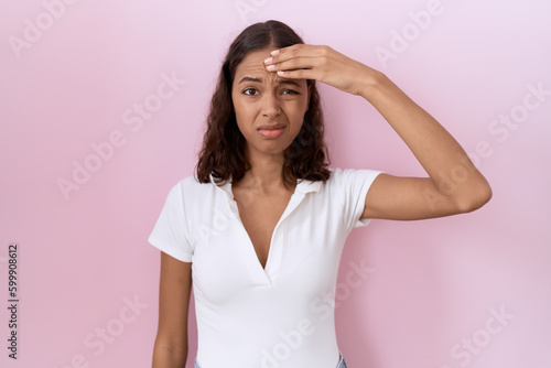 Young hispanic woman wearing casual white t shirt worried and stressed about a problem with hand on forehead, nervous and anxious for crisis