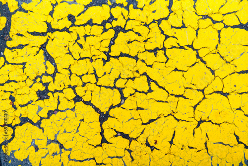 Yellow cracked paint on wet asphalt road