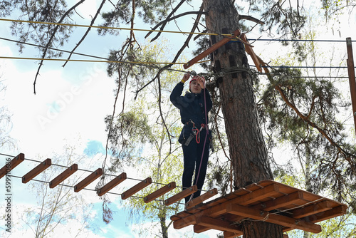 a teenage girl passes an obstacle in a rope park