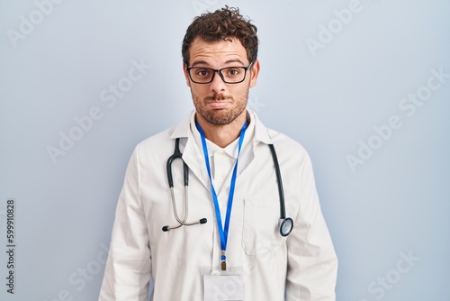Young hispanic man wearing doctor uniform and stethoscope depressed and worry for distress, crying angry and afraid. sad expression.