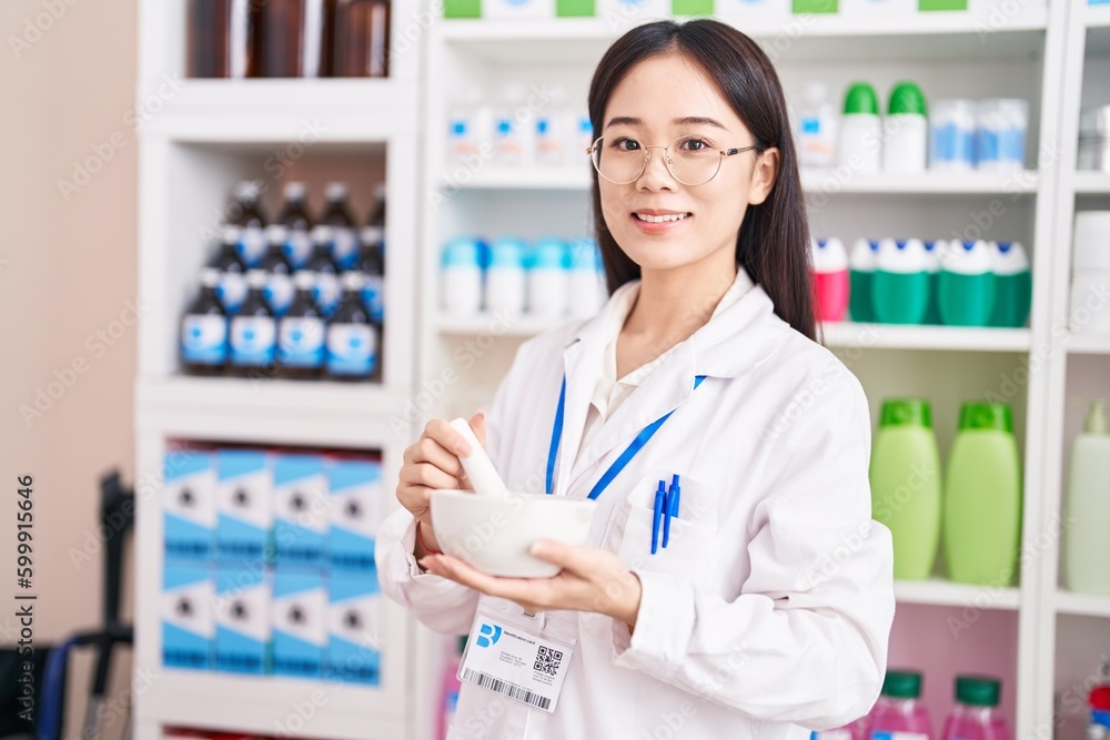 Young chinese woman pharmacist smiling confident make mixture at pharmacy