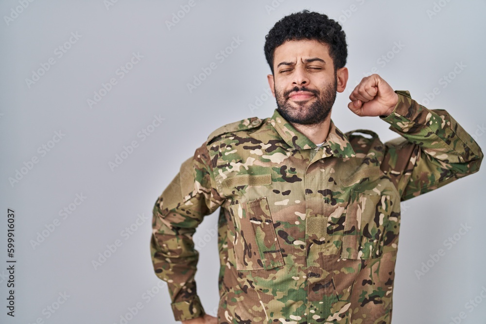 Arab man wearing camouflage army uniform stretching back, tired and relaxed, sleepy and yawning for early morning