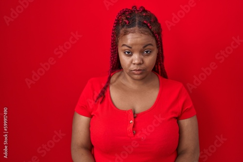 African american woman with braided hair standing over red background skeptic and nervous, frowning upset because of problem. negative person. © Krakenimages.com