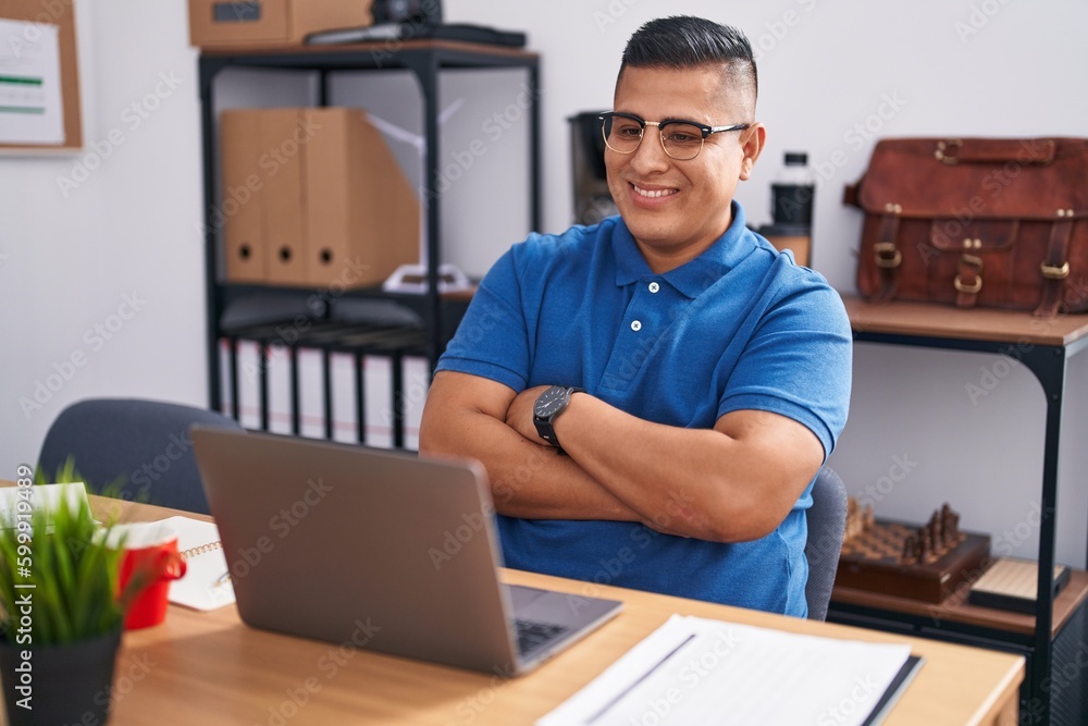 Young hispanic man working at the office with laptop happy face smiling with crossed arms looking at the camera. positive person. Young hispanic man working at the office with laptop happy face smiling with crossed arms looking at the camera. positive person.