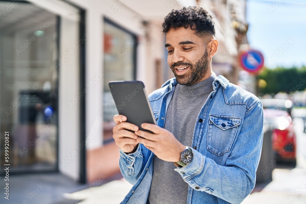Young hispanic man smiling confident using touchpad at street Young hispanic man smiling confident using touchpad at street