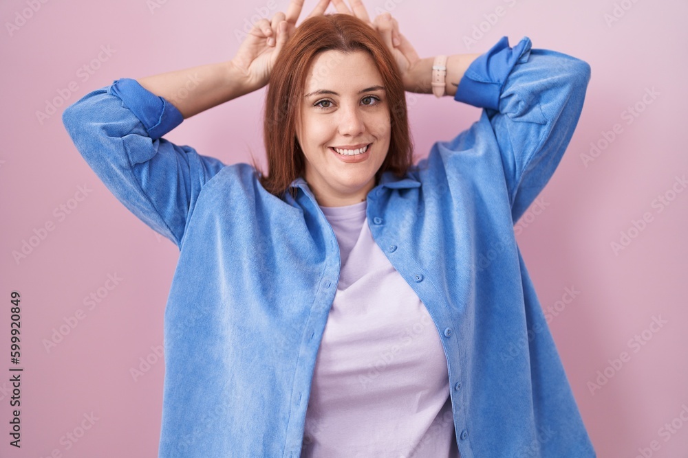 Young hispanic woman with red hair standing over pink background posing funny and crazy with fingers on head as bunny ears, smiling cheerful Young hispanic woman with red hair standing over pink background posing funny and crazy with fingers on head as bunny ears, smiling cheerful