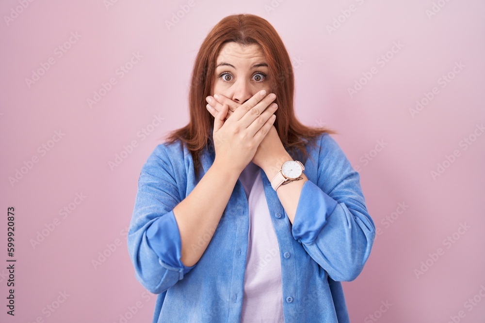 Young hispanic woman with red hair standing over pink background shocked covering mouth with hands for mistake. secret concept. Young hispanic woman with red hair standing over pink background shocked covering mouth with hands for mistake. secret concept.