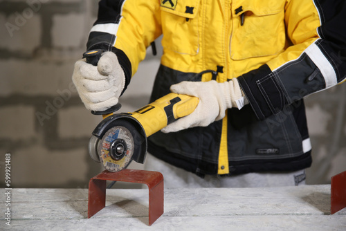 Locksmith in special clothes and goggles works in production. Worker. A man in a helmet and with a grinder in his hand. Industry. Builder. Metal processing with angle grinder