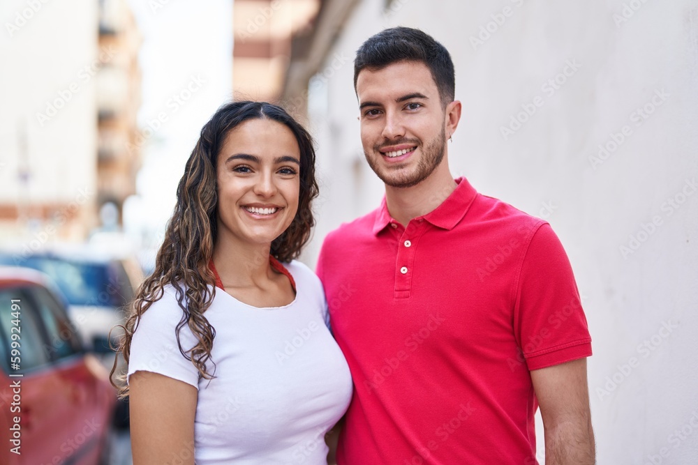 Fototapeta premium Young hispanic couple smiling confident hugging each other at street