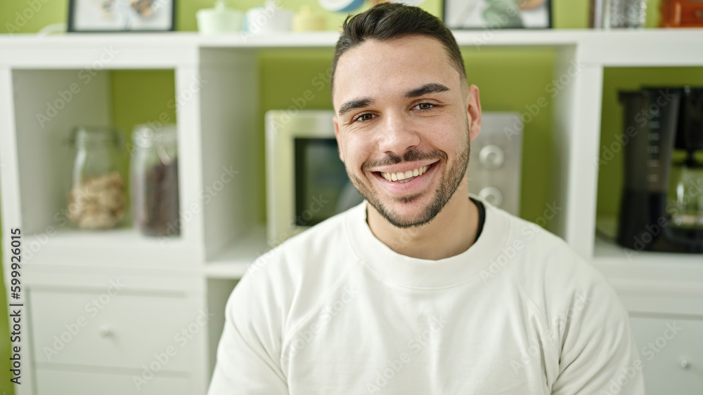 Young hispanic man smiling confident sitting on table at dinning room Young hispanic man smiling confident sitting on table at dinning room