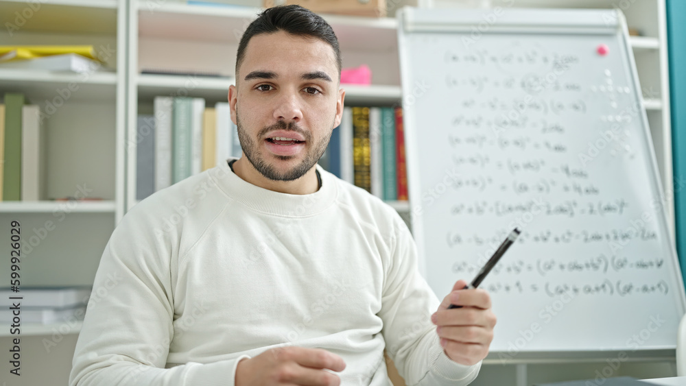 Young hispanic man teacher teaching maths lesson at library university Young hispanic man teacher teaching maths lesson at library university