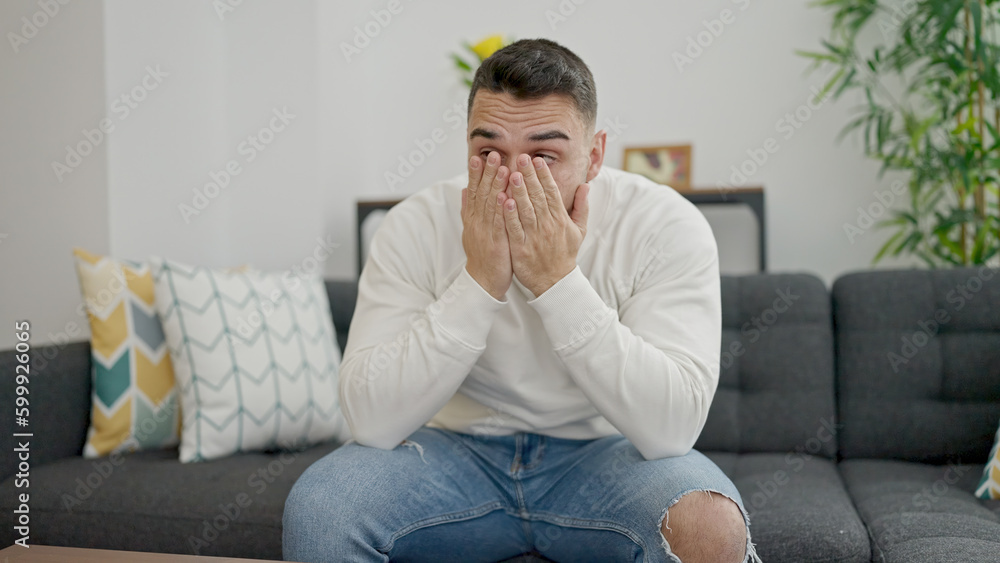 Young hispanic man stressed sitting on sofa at home Young hispanic man stressed sitting on sofa at home