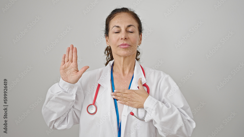 Middle age hispanic woman doctor making an oath with hand on chest over isolated white background Middle age hispanic woman doctor making an oath with hand on chest over isolated white background