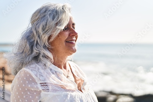 Middle age woman smiling confident breathing at seaside