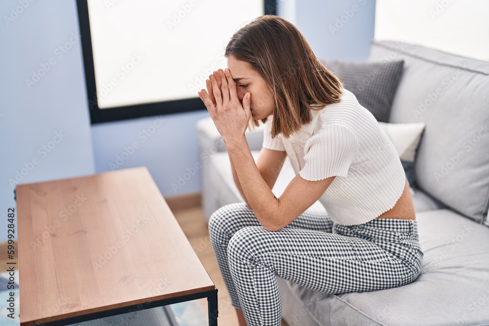 Young beautiful hispanic woman stressed sitting on sofa at home Young beautiful hispanic woman stressed sitting on sofa at home
