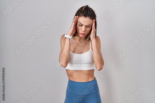 Hispanic woman wearing sportswear over isolated background with hand on head, headache because stress. suffering migraine.