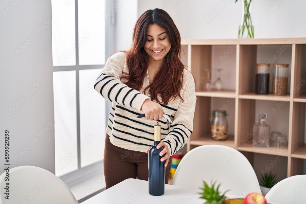 Young hispanic woman smiling confident uncorking red wine bottle at home Young hispanic woman smiling confident uncorking red wine bottle at home
